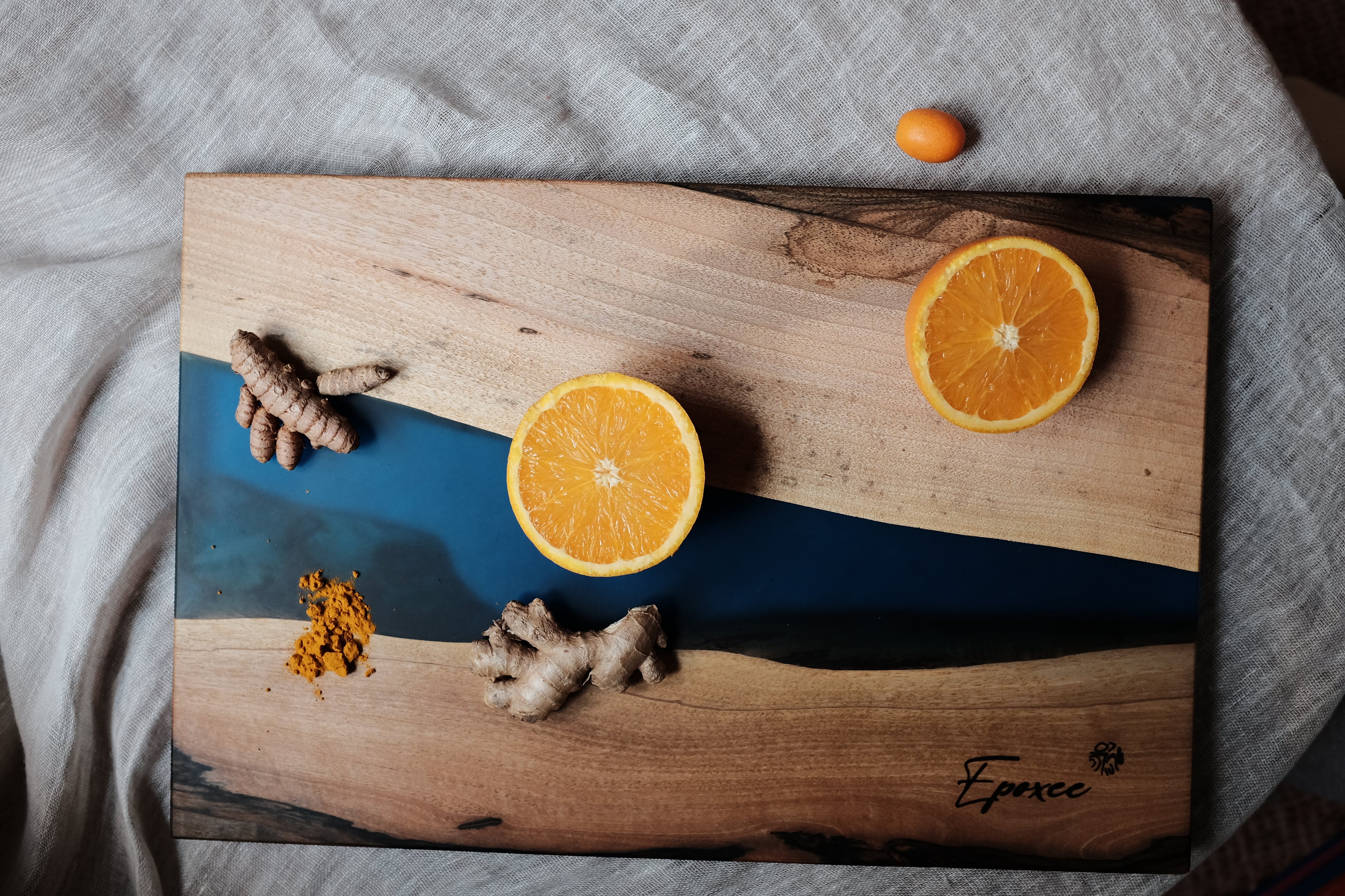 Epoxy blue wooden serving board with oranges and ginger arranged on top as decorative elements