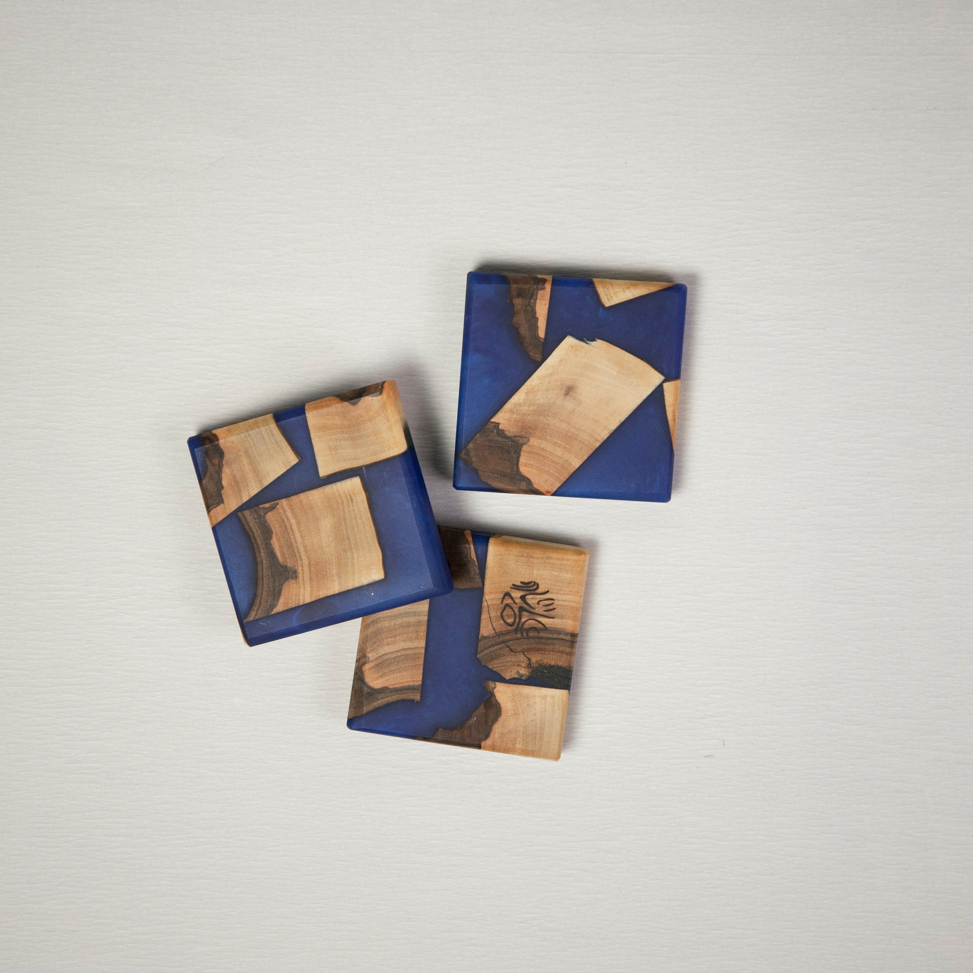 Three coasters made from wood and epoxy resin in the color deep saphire