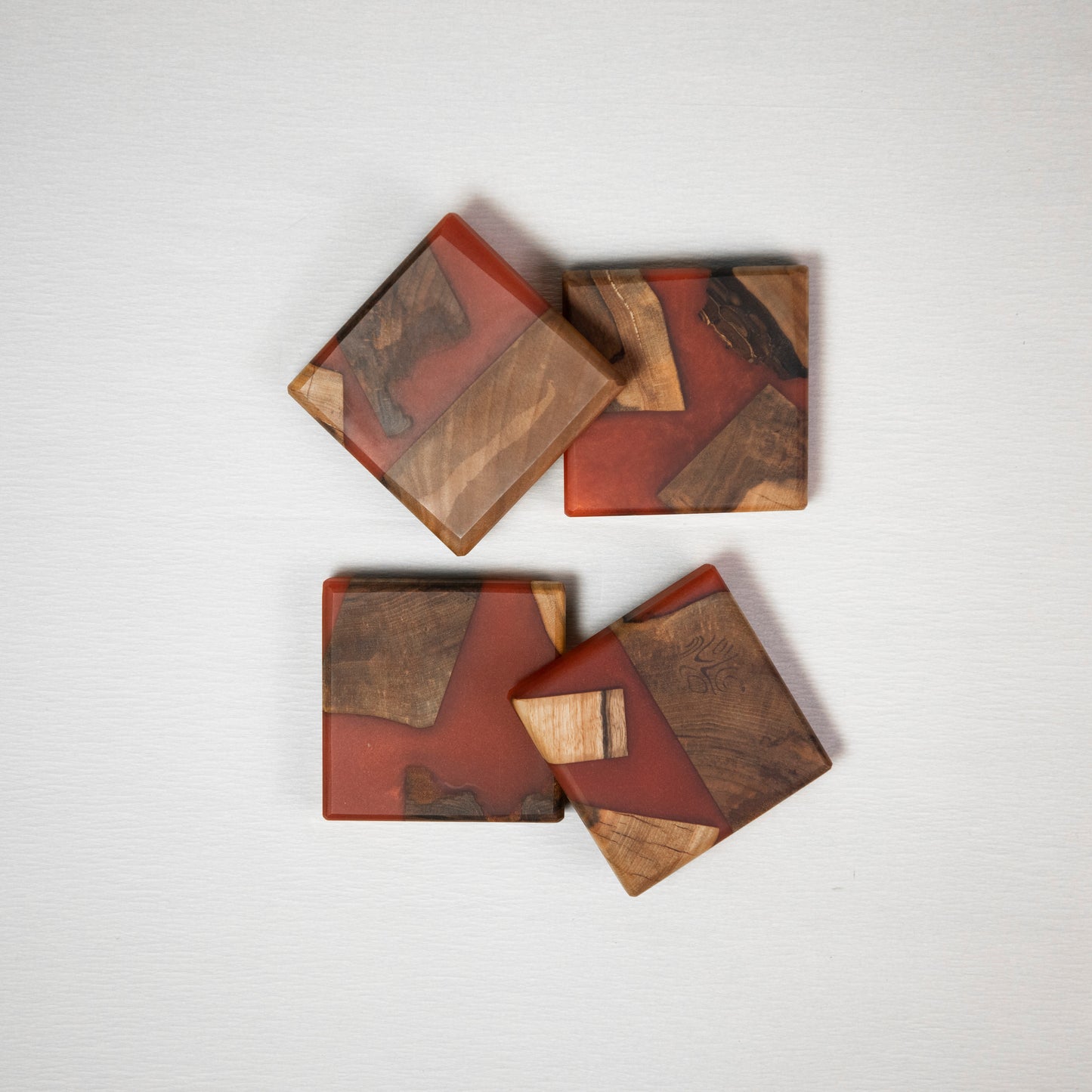 Four coasters made from wood and epoxy resin in the color red orange