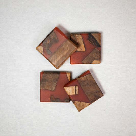 Four coasters made from wood and epoxy resin in the color red orange