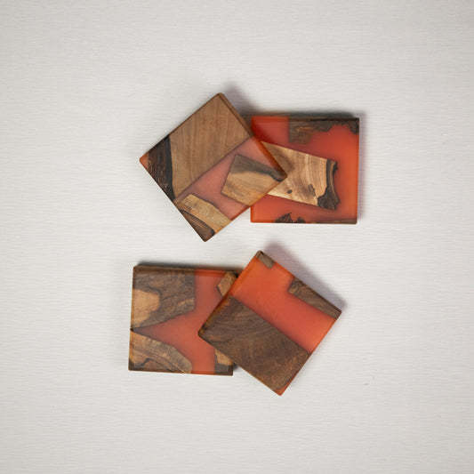 Four coasters made from wood and epoxy resin in the color siena orange